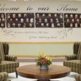 A cozy seating area with a welcome sign and a display of photographs on the wall.