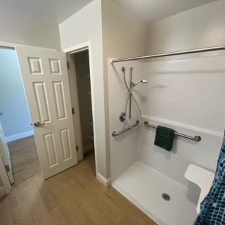 An accessible bathroom featuring a shower with grab bars and an open doorway.