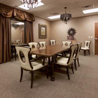 A well-appointed conference room with a large table and eight chairs, featuring elegant lighting and decor.