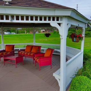 A cozy gazebo with colorful outdoor furniture set amidst a lush green lawn.
