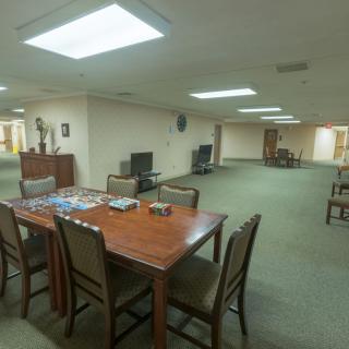 An interior view of a spacious office area with multiple tables and chairs, illuminated by bright ceiling lights.