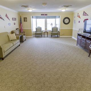 A cozy living room with a sofa, chairs, and a television, decorated with wall pennants and featuring carpeted flooring.