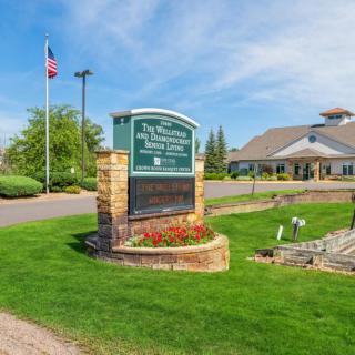 Entrance to a golf club with a welcoming sign and well-maintained landscape.