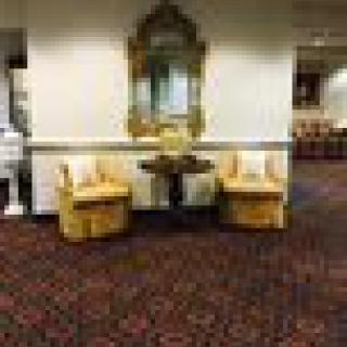 A cozy lobby seating area with two yellow chairs, a small table, and a decorative mirror on the wall.