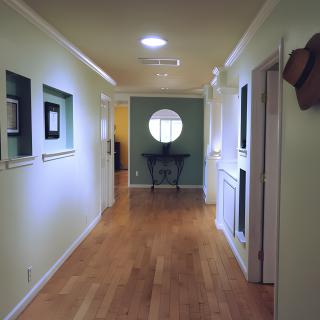 A well-lit hallway with wooden floors and artwork on the walls.