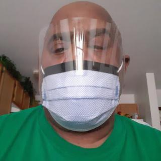 A person wearing a face shield and surgical mask indoors.