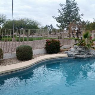 A serene outdoor pool area with surrounding greenery and a decorative rock feature.