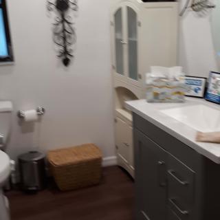 A well-organized bathroom featuring a sink, mirror, cabinet, and various decor items.