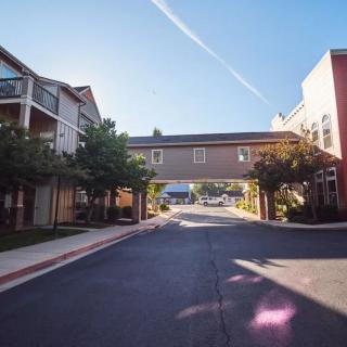An apartment complex with connected buildings and landscaped surroundings under a clear sky.