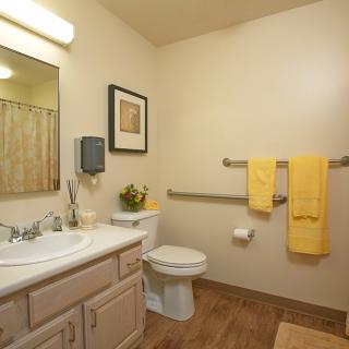 A clean and well-organized bathroom featuring yellow towels and simple decor.