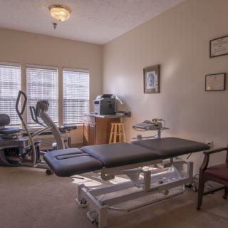 A therapy room equipped with exercise machines and a treatment table.