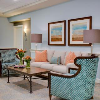 A cozy living room featuring a neutral sofa with colorful cushions, matching armchairs, and elegant wall art.
