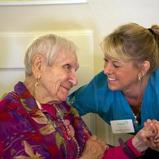 A caregiver shares a warm moment with an elderly woman.