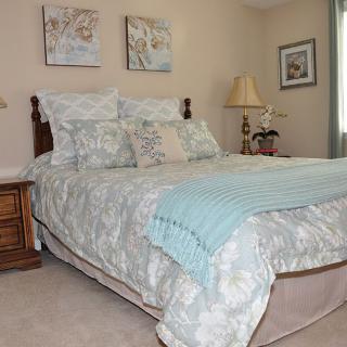 A cozy bedroom with a neatly made bed, decorative pillows, and calming artwork on the walls.