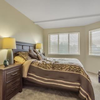 A cozy bedroom with a neatly made bed, bedside tables, and warm lighting.