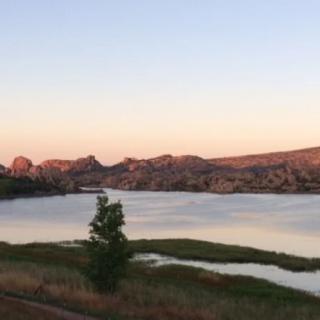 A tranquil lake at sunset with mountains in the background.