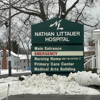 Signage for Nathan Littauer Hospital, indicating the main entrance and emergency services amidst snowy conditions.