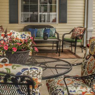A cozy patio setup with floral-cushioned chairs, a table, and vibrant flowers.