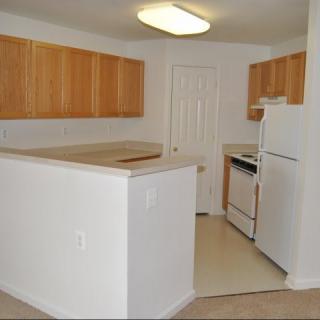 A modern kitchen with wooden cabinets and white appliances.