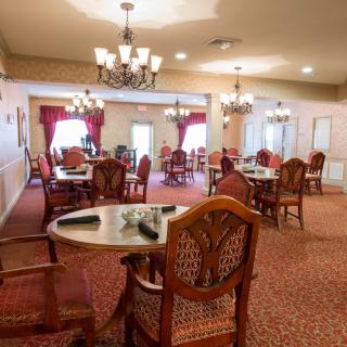 A well-lit dining room with elegant wooden furniture and chandeliers.