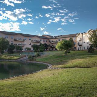 A residential building overlooking a serene pond surrounded by greenery.