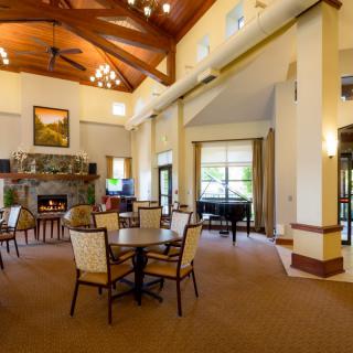 A spacious and elegant lounge with high ceilings, featuring a grand piano and a fireplace.