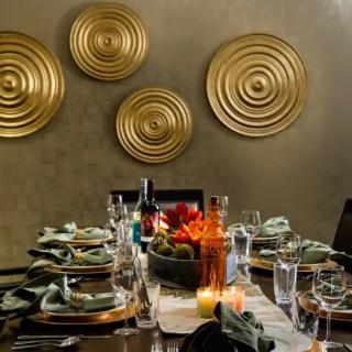 An elegantly set dining table with gold wall art and a centerpiece, ready for a formal gathering.