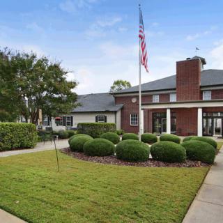 A building with a neatly landscaped lawn, featuring an American flag and a clear blue sky.