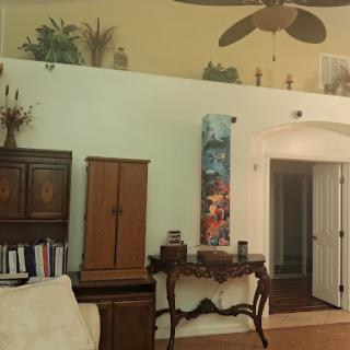 A cozy living room featuring a wooden cabinet, decorative wall art, and a ceiling fan.