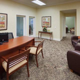 A view of a professional office space with a desk, chairs, and decorative artwork.