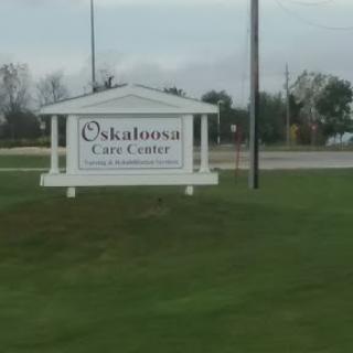 Signage for the Oskaloosa Care Center in a grassy area.
