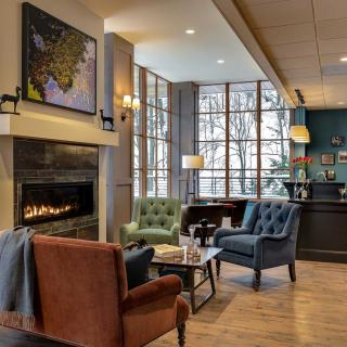 A cozy living room with a fireplace, seating area, and large windows.