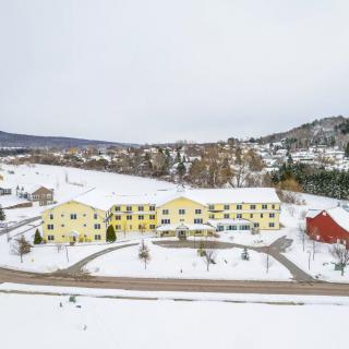 Aerial view of a small town blanketed in snow, featuring yellow buildings and a stark winter landscape.