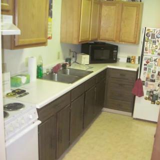 A cozy kitchen with wooden cabinets, a microwave, and a fridge adorned with magnets.