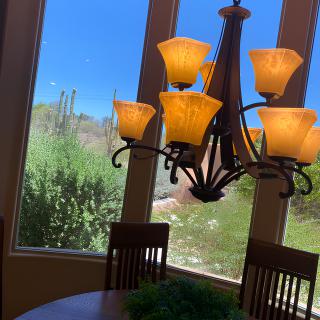 A cozy dining room with a warm chandelier and large windows showcasing a natural outdoor view.