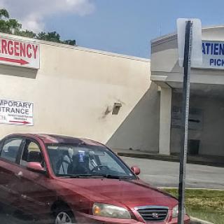 A red car parked outside an urgent care facility.