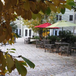 A cozy courtyard with tables and colorful umbrellas surrounded by autumn leaves.
