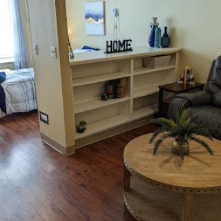 A cozy living room setup featuring a plush couch, decorative shelf, and a wooden coffee table.