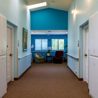 An office hallway with blue walls and a small waiting area at the end.