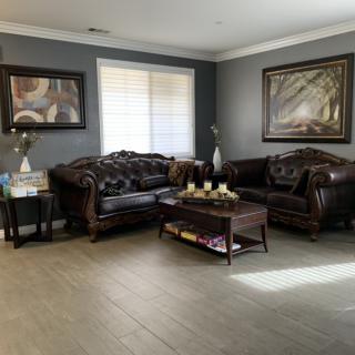 A well-decorated living room with leather sofas, a central coffee table, and framed artwork on the walls.