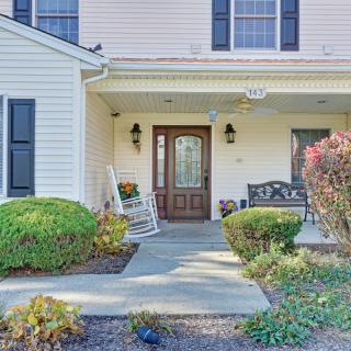 A welcoming front porch of a residential house with a rocking chair and landscaped walkway.