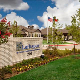 Entrance to Larkspur, featuring a landscaped area with flags and signage.