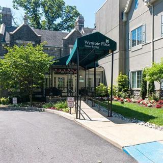 Entrance to a hotel with an awning and landscaped surroundings.