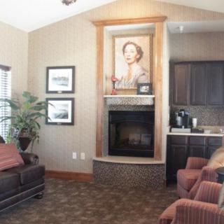 A cozy living room featuring a fireplace with an elegant portrait above it and comfortable seating.