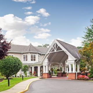 A scenic view of a hotel entrance with a covered driveway and landscaped surroundings.