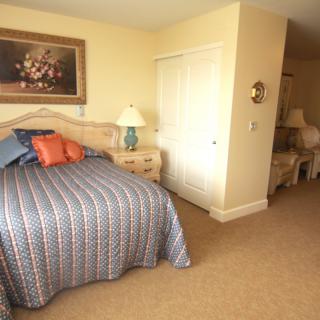 A cozy bedroom with a patterned bedspread and decorative pillows, featuring wooden furniture and warm lighting.