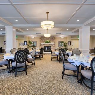 An elegantly designed dining room featuring neatly arranged tables and chairs, complemented by stylish chandeliers and tasteful decor.
