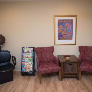 A cozy waiting room with chairs, a table, and a magazine rack.
