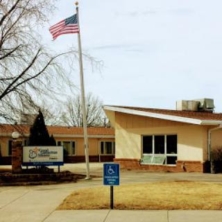 A view of a building with an American flag flying, featuring a handicap accessible sign.