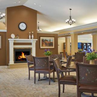 A cozy lounge area with a fireplace, elegant chairs, and tables.